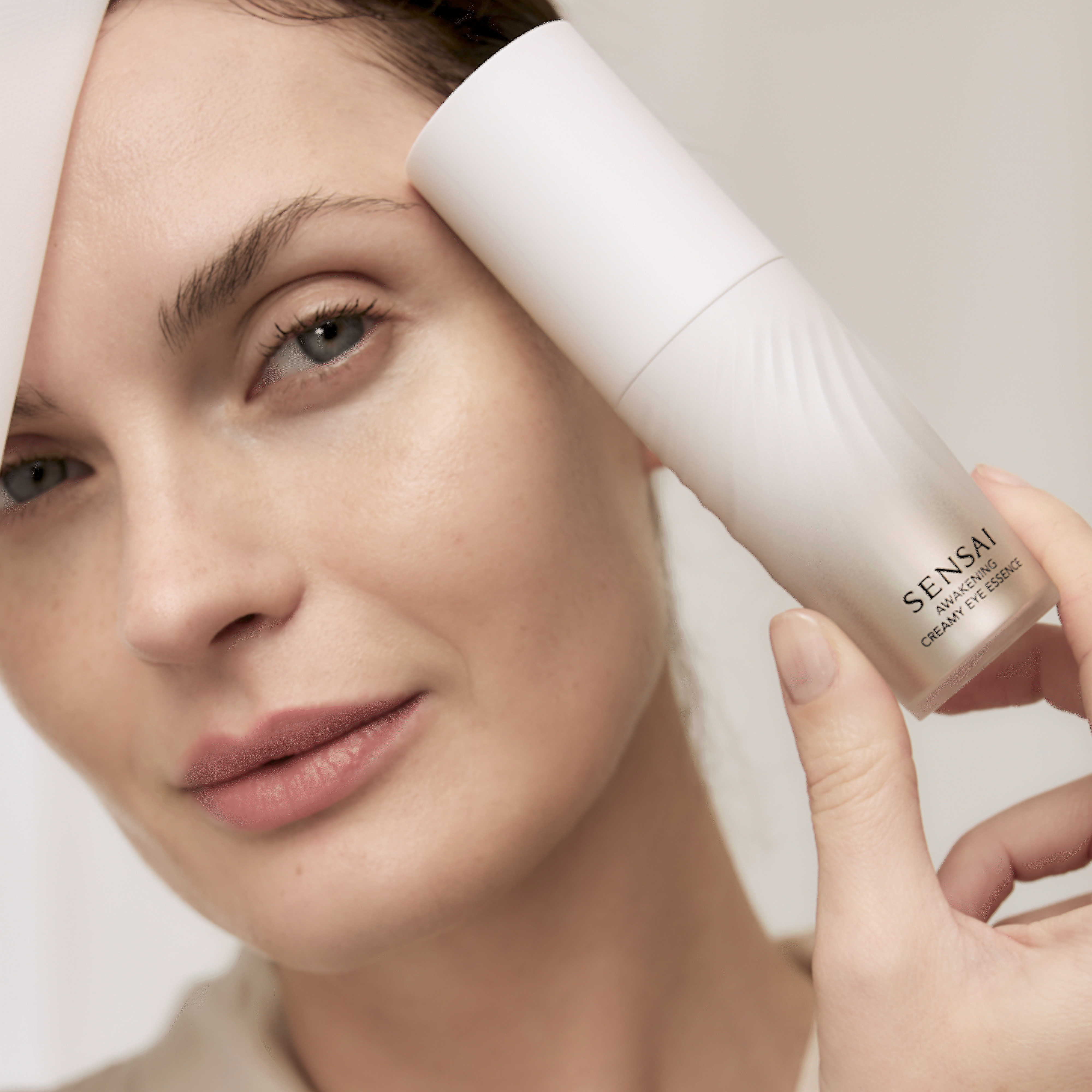 Awakening Creamy Eye Essence bottle being held and product being applied by model